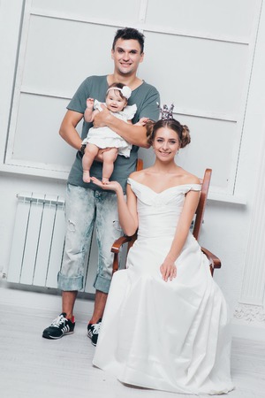 a little girl in the hands of the Prince and Princess. a man and a woman in suits holding a child in their armsの写真素材