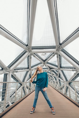 a woman stands on a bridge inside a glass tunnelの写真素材