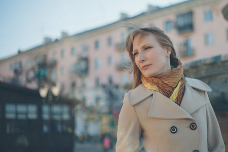 beautiful girl walking down the street in a coat, the wind waving her hairの写真素材