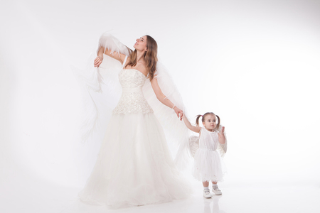 a woman and a girl in white dresses with angel wings on his back. Big and small angel on white backgroundの写真素材