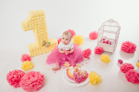 a little girl eats cake with her hands. The baby was covered in food. isolated white background. birthday partyの写真素材