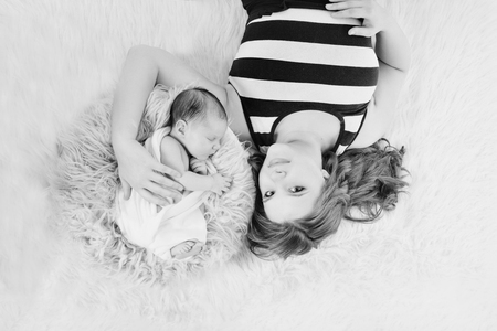 portrait of mother and newborn baby face to face. woman and child lying on the floorの写真素材