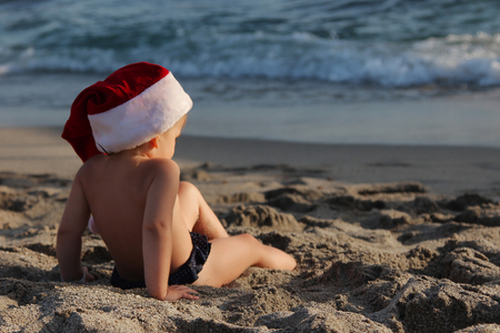 Funny little girl sitting on the beach. Christmas and new year vacations concept.の写真素材