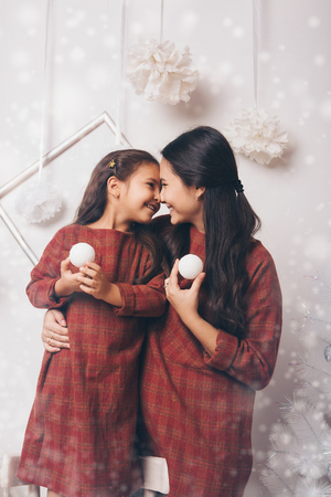 woman and girl holding white snowballs-toys on snow backgroundの写真素材