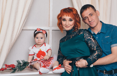 Christmas concept: woman, man and a girl with a fir branch, a cone and Rowan berries in her handsの写真素材