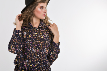 beautiful girl in loose-fitting clothes with a hat in her hands on a white background. Model shows clothes and accessoriesの写真素材
