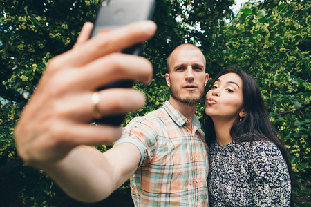 A guy with a girl taking selfies on a green foliage background. Valentines dayの写真素材