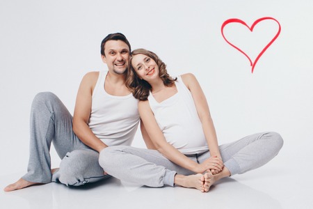 Family portrait: the husband embraces the pregnant wife on a white background. pregnant couple in love. Valentines dayの写真素材