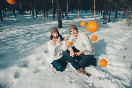 Valentine's day: couple in love with oranges on the background of winter landscapeの写真素材