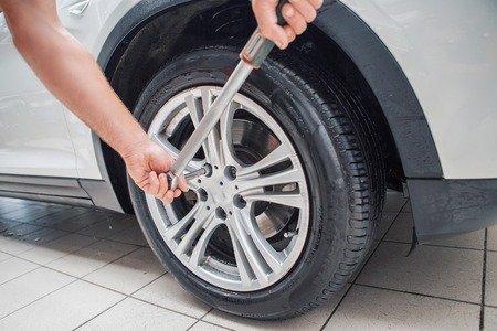 car repair: wheel replacement closeup. mechanic screwing or unscrewing car wheel at car service garageの写真素材