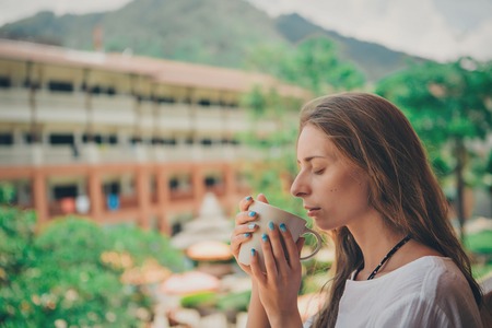 beautiful girl with long hair and blue manicure holding a large mug