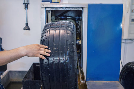 car repair: wheel replacement closeup. mechanic screwing or unscrewing car wheel at car service garageの写真素材