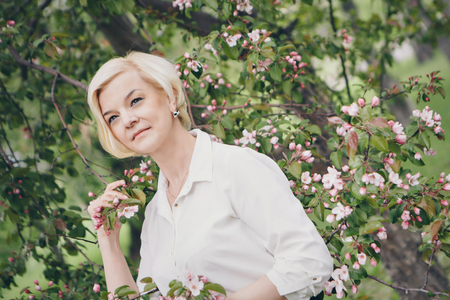 portrait of a beautiful blonde with short hair among flowersの写真素材