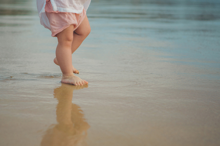 Legs of children stand on the beach. Baby feet in the sand. Summer beach background. Summertime holidays concept.の写真素材