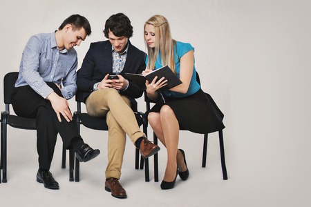 business people waiting in queue sitting in row holding smartphones and cvs, human resources, employment and hiring conceptの写真素材