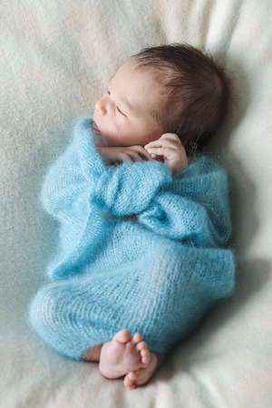 newborn baby sleeps wrapped in a blanketの写真素材