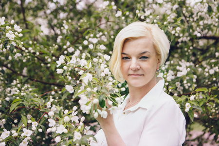 portrait of a beautiful blonde with short hair among flowersの写真素材