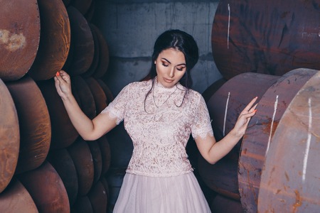 March 8: portrait of beautiful girl in a light dress among metal pipesの写真素材