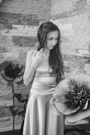 March 8: beautiful girl with long hair next to a huge artificial flowerの写真素材