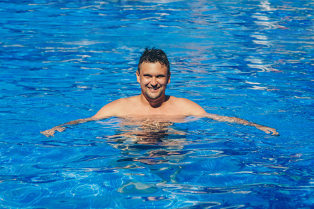 tanned man on vacation swimming in the poolの写真素材