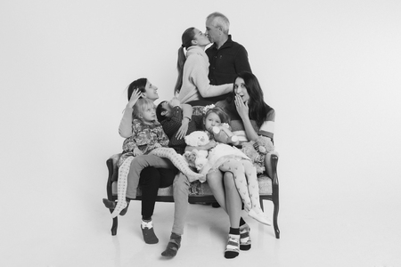 group of people on a white background: adults and children with toys sitting on the same couchの写真素材