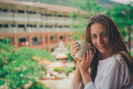beautiful girl with long hair and blue manicure holding a large mugの写真素材