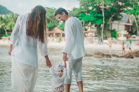 Cute baby learning to walk and make his first steps. mom is holding his hand. child's feet close up, copy spaceの写真素材