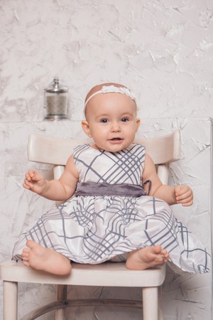 a little girl in a dress sits on a chair and smilesの写真素材