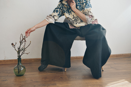 women's feet in linen clothes in japanese and shoes next to a flower on a white backgroundの写真素材