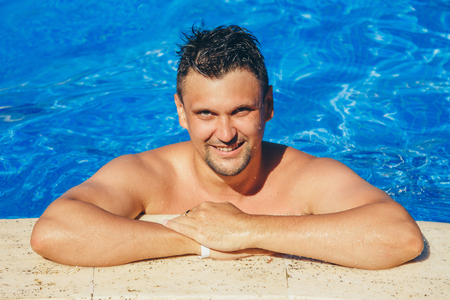tanned man on vacation swimming in the poolの写真素材