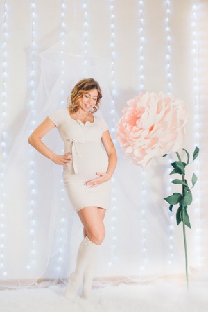 March 8: beautiful pregnant girl with long hair next to a huge artificial flowerの写真素材