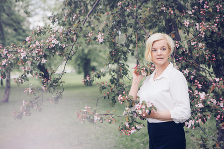 portrait of a beautiful blonde with short hair among flowersの写真素材