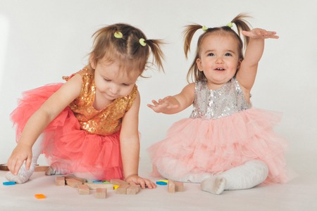 two little girls playing on the floor on a white backgroundの写真素材