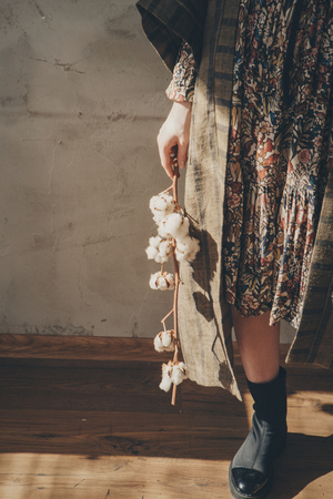 womens feet in linen clothes and shoes next to a flower on a white backgroundの写真素材