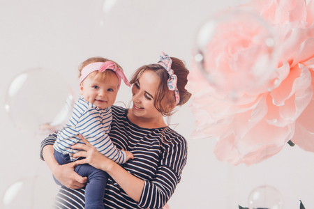 the child in the arms of his mother on white background. A woman with a child in her arms next to a large flowerの写真素材