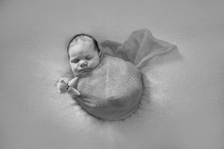 newborn baby sleeping with a toy next to the knitted teddy bearの写真素材