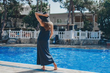 pregnant woman with long hair in blue dress posing in waterの写真素材