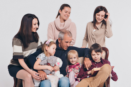 group of people on a white background: adults and children with toys sitting on the same couchの写真素材