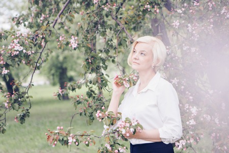 portrait of a beautiful blonde with short hair among flowersの写真素材
