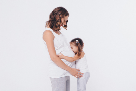 Happy kid girl hugging pregnant mother's belly, pregnancy and new life conceptの写真素材