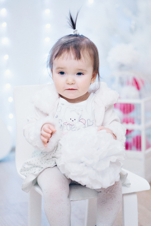 a little girl in a dress sits on a chair and smilesの写真素材