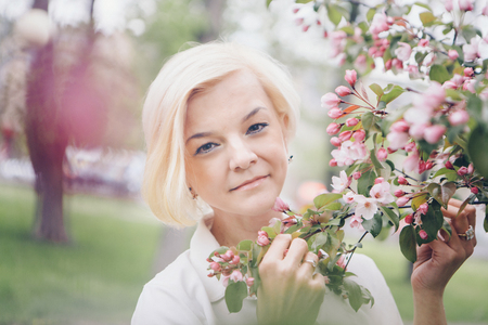 portrait of a beautiful blonde with short hair among flowersの写真素材
