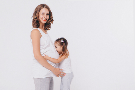 Happy kid girl hugging pregnant mother's belly, pregnancy and new life conceptの写真素材