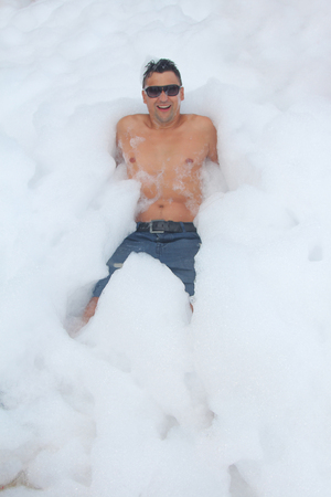 the man in glasses has fun in the white foamの写真素材