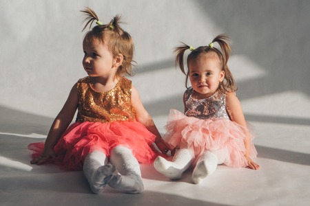 two little girls playing on the floor on a white backgroundの写真素材