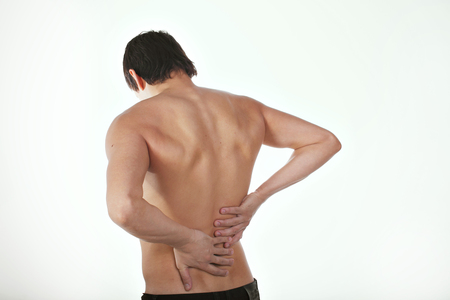 back pain: a man on a white background holding his sore torso