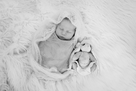 newborn baby sleeping with a toy next to the knitted teddy bearの写真素材