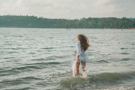 girl with long hair in white shirt posing in waterの写真素材