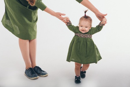Cute baby learning to walk and make his first steps. mom is holding his hand. child's feet close up, copy spaceの写真素材