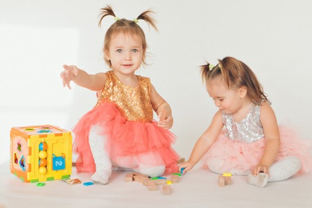 two little girls playing on the floor on a white backgroundの写真素材
